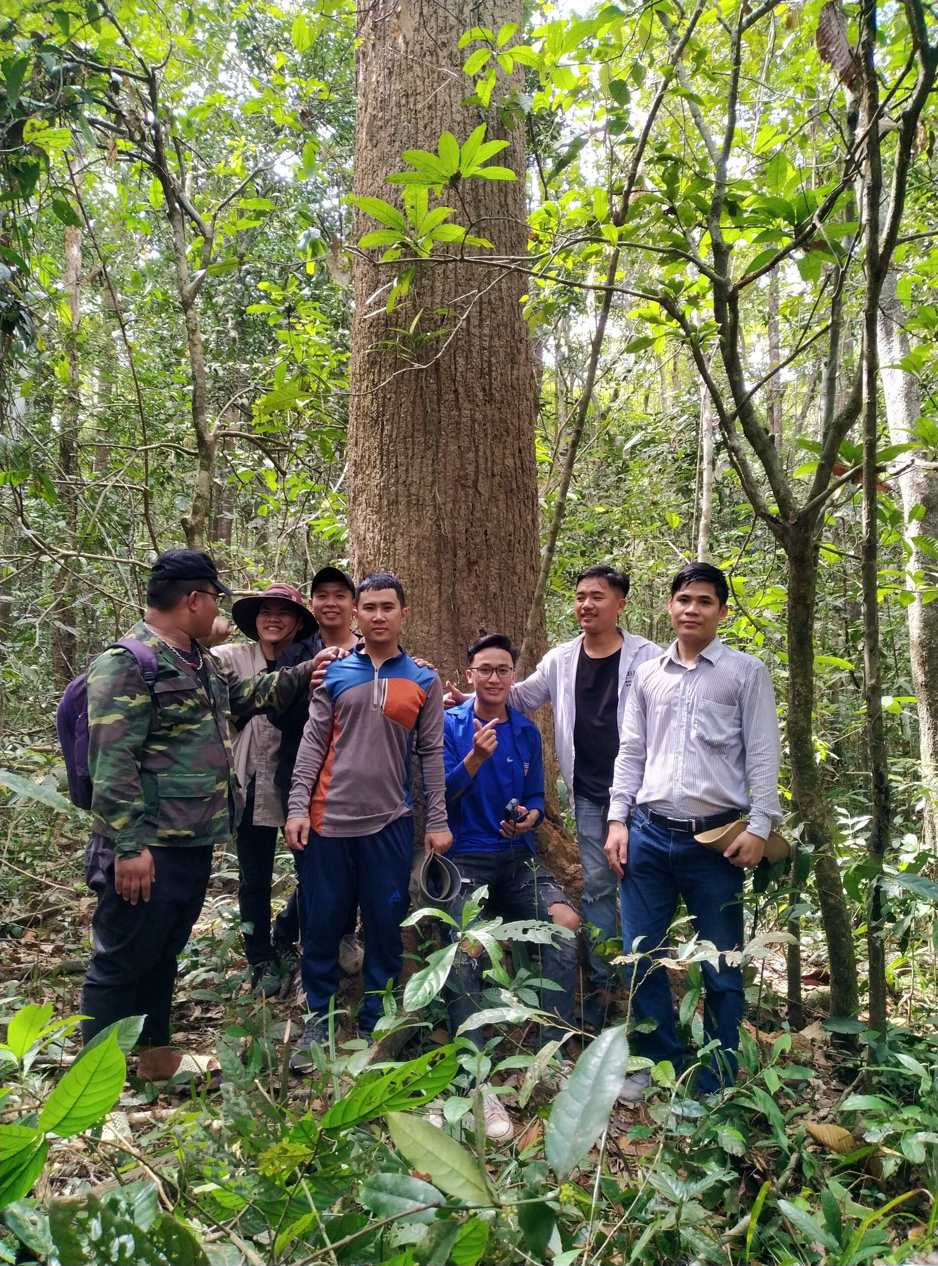 A group of men standing in front of a treeDescription automatically generated with medium confidence